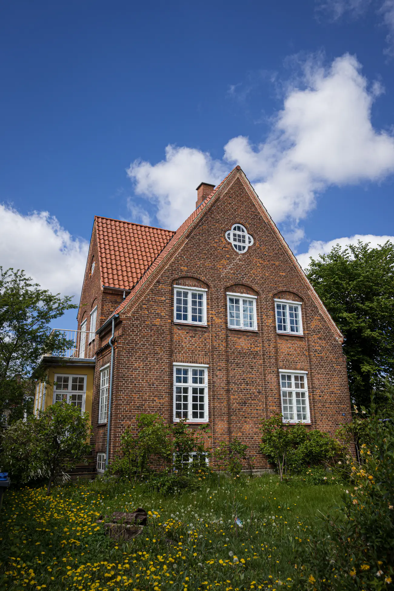 Et dansk murstenshus med tegltag set fra haven