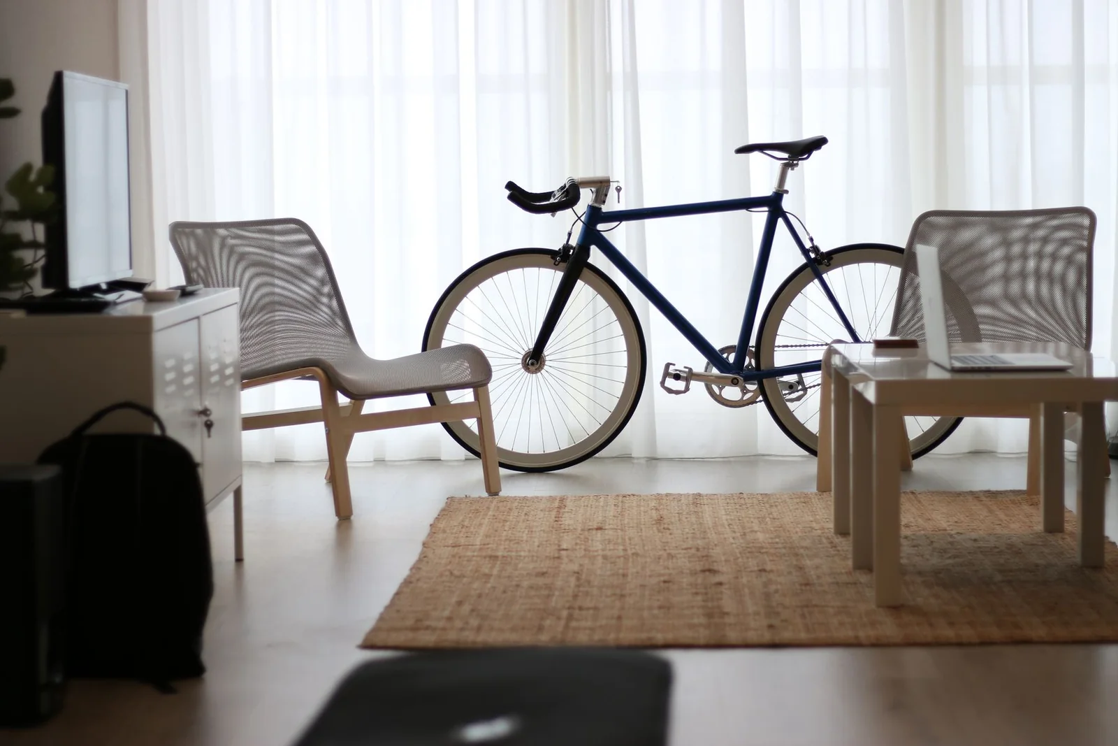 En stue med møbler, tv og en cykel ved vinduet