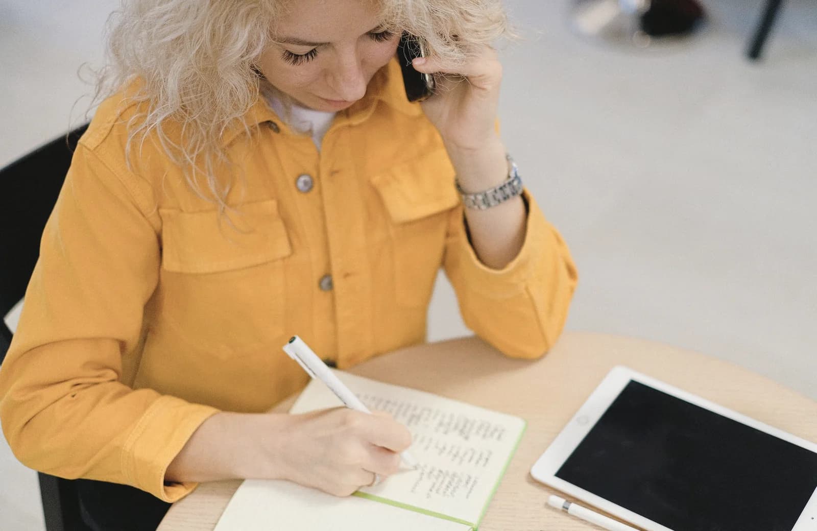 En kvinde tager noter under en telefonsamtale