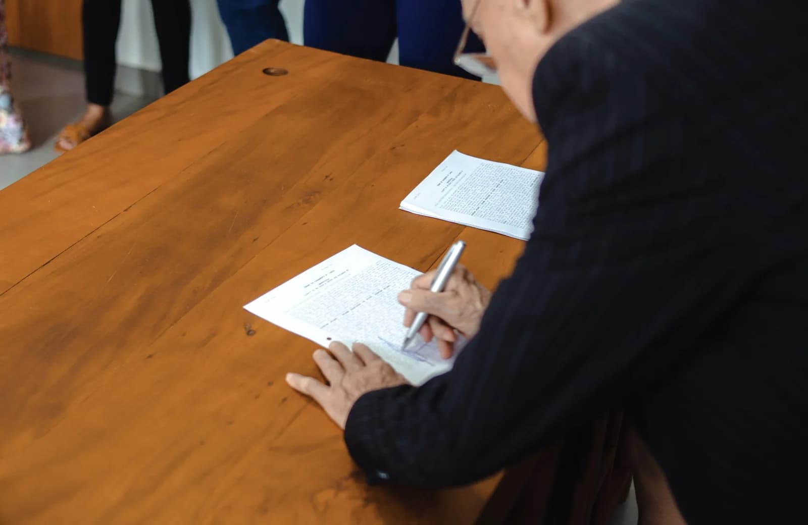 En person udfylder dokumenter ved et bord