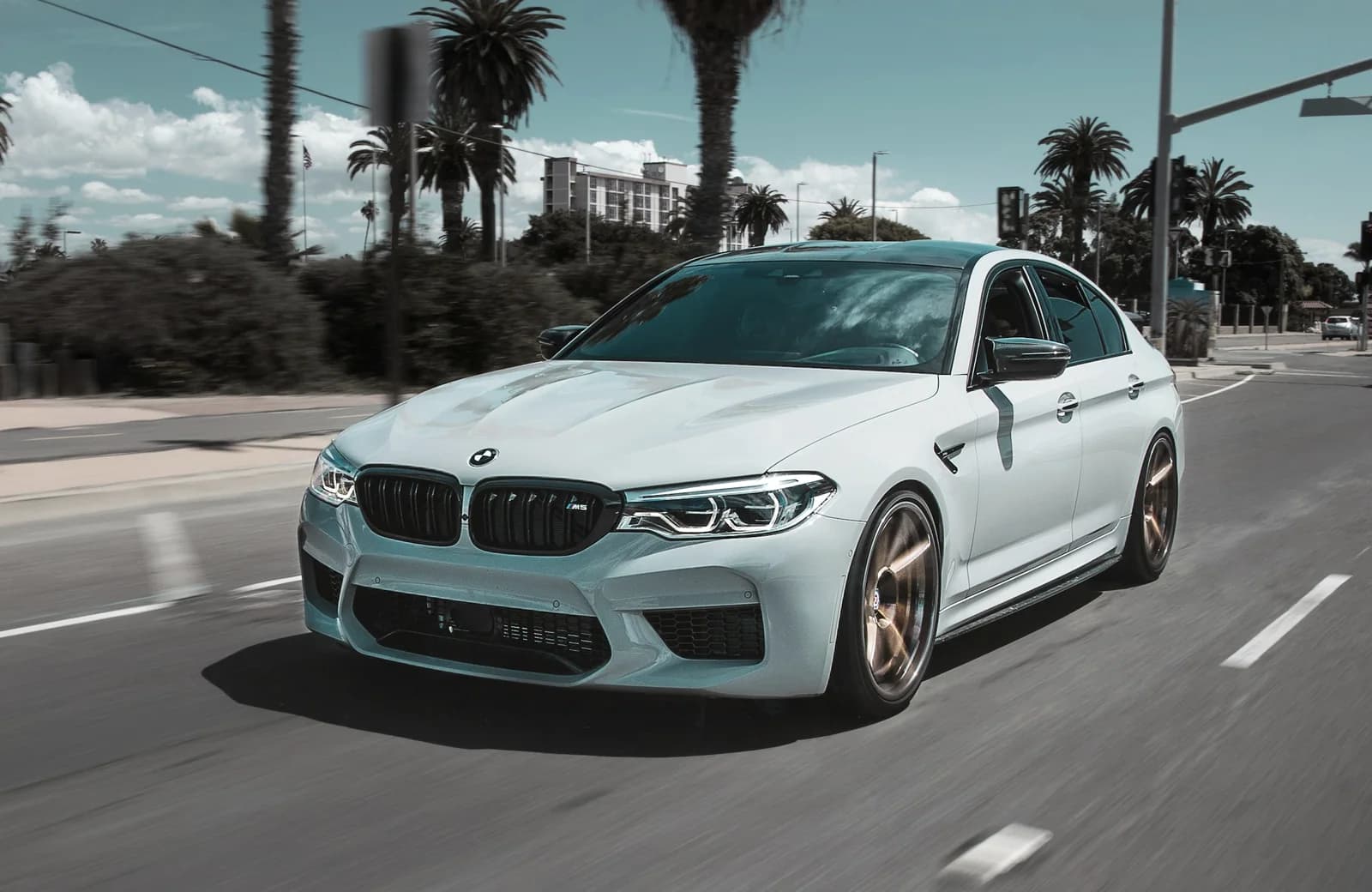 En blå BMW parkeret ved en grøn vejkant
