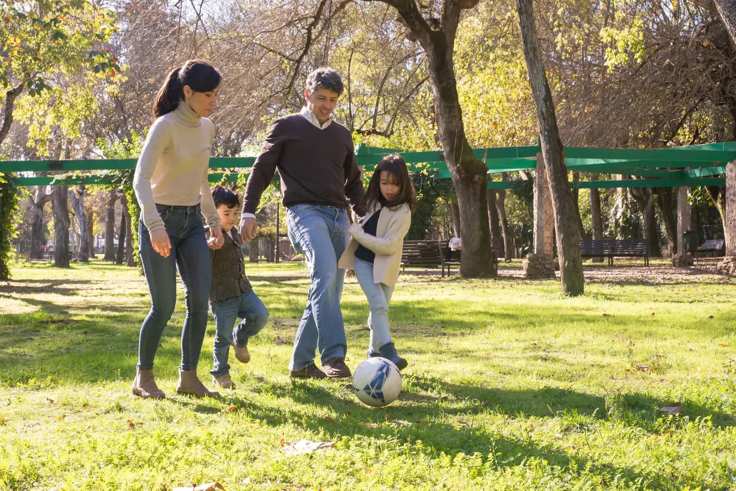 En familie spiller fodbold sammen i en park